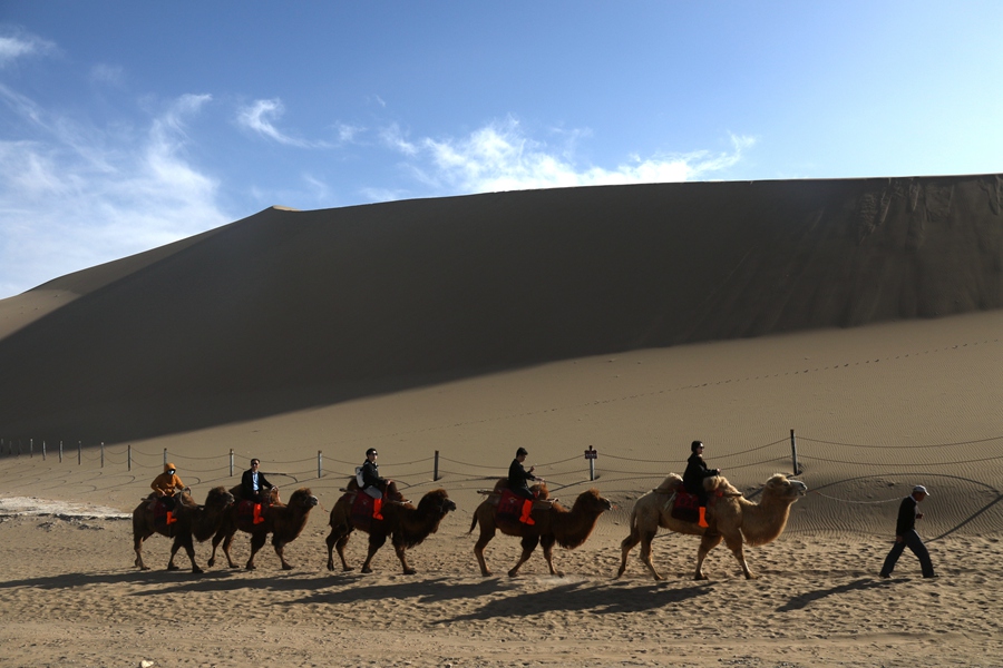 Tourists enjoy picturesque spring views of desert in Dunhuang, NW China's Gansu
