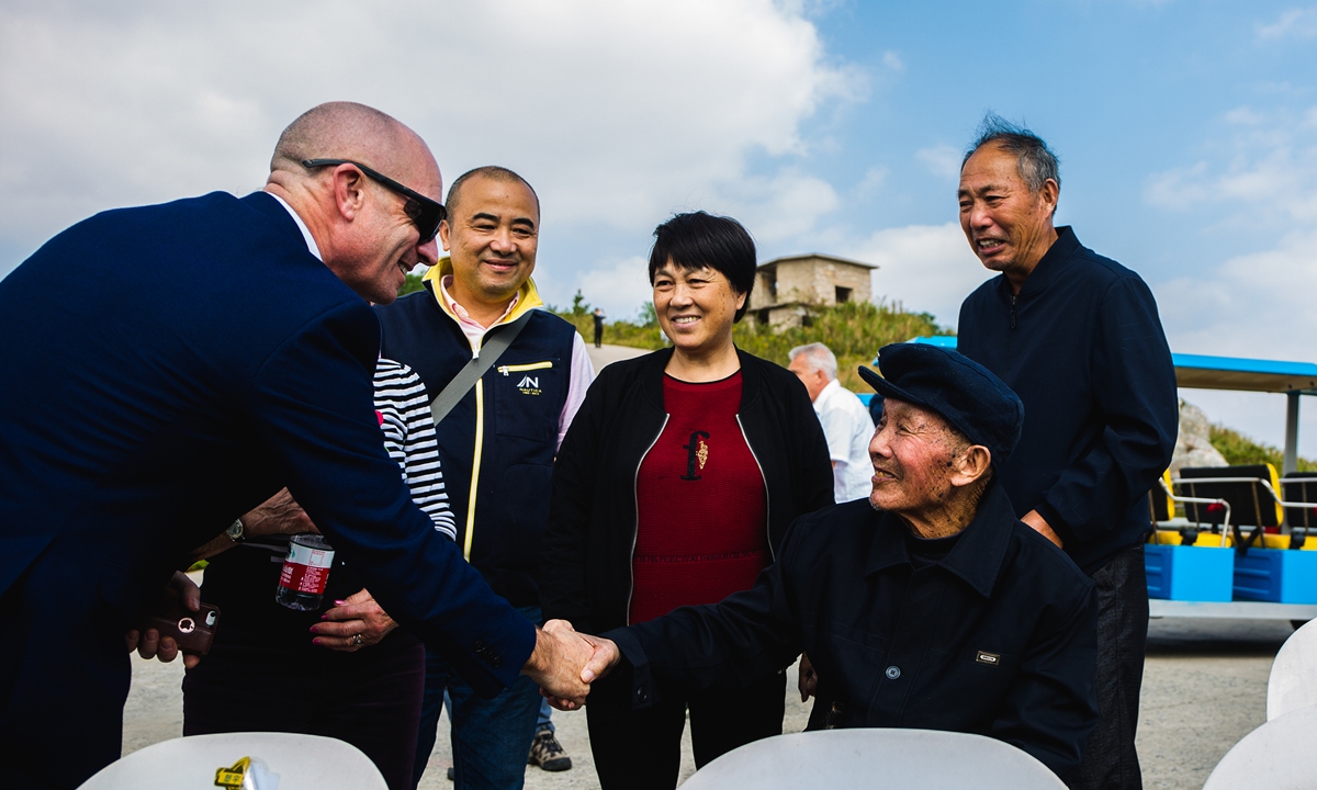 A relative of a British POW shakes hands with Chinese fisherman Lin Agen (in the hat) who helped rescue POWs during the sinking of the Lisbon Maru in 1942, in October 2019. Photo: Courtesy of Fang Li